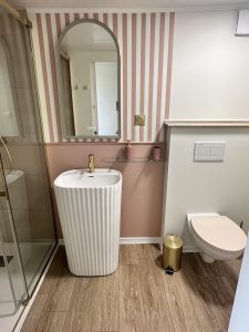 WC suspendu et vasque blanche, carrelage rayé rose, salle d'eau du gîte
