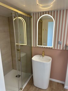 Salle d'eau moderne avec douche à l'italienne et miroir arrondi doré